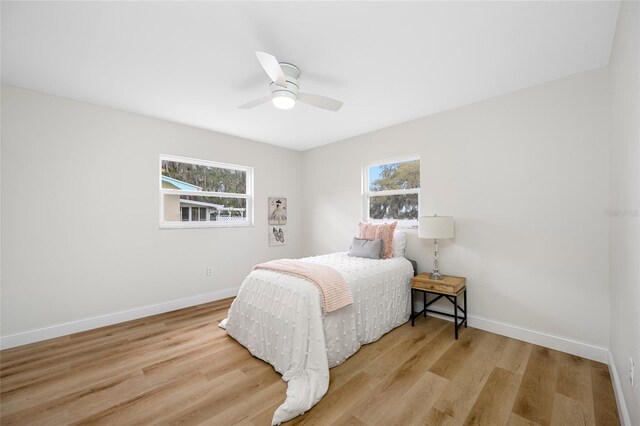 bedroom featuring baseboards, multiple windows, and wood finished floors