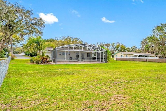 rear view of property featuring a lanai, a yard, fence, and a patio