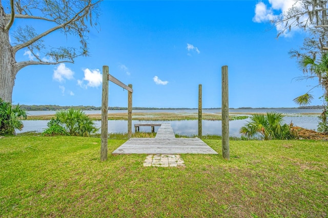 view of dock with a yard and a water view