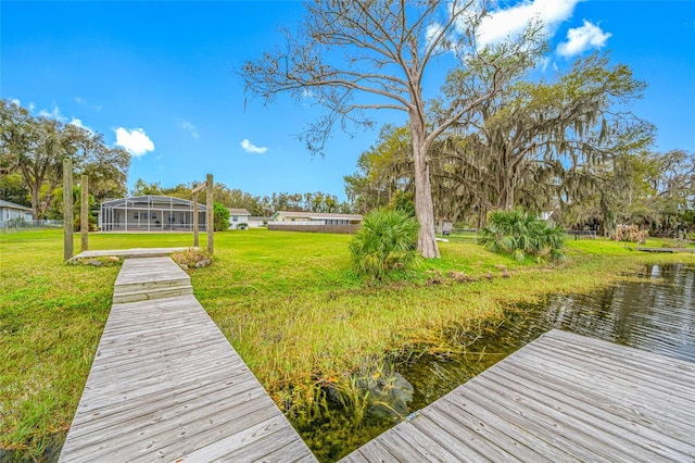 view of dock with a lawn and a water view