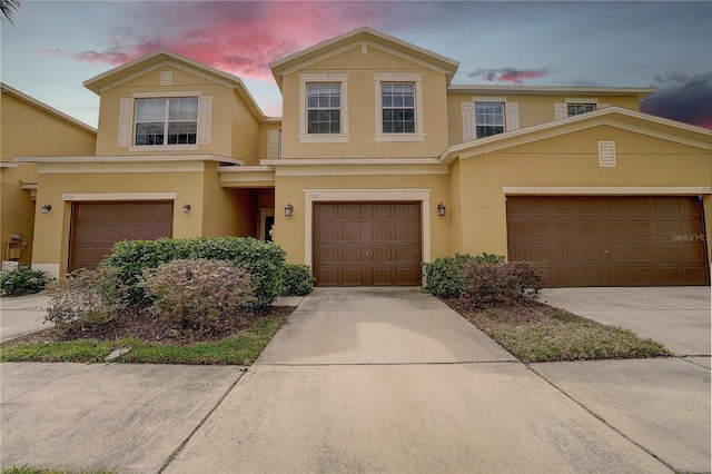 traditional home with concrete driveway, an attached garage, and stucco siding