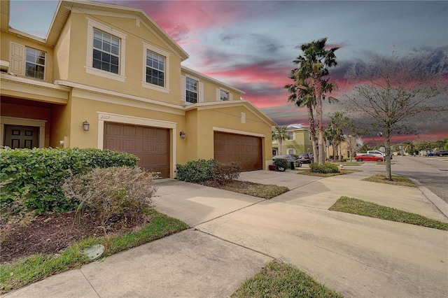 townhome / multi-family property with an attached garage, concrete driveway, and stucco siding