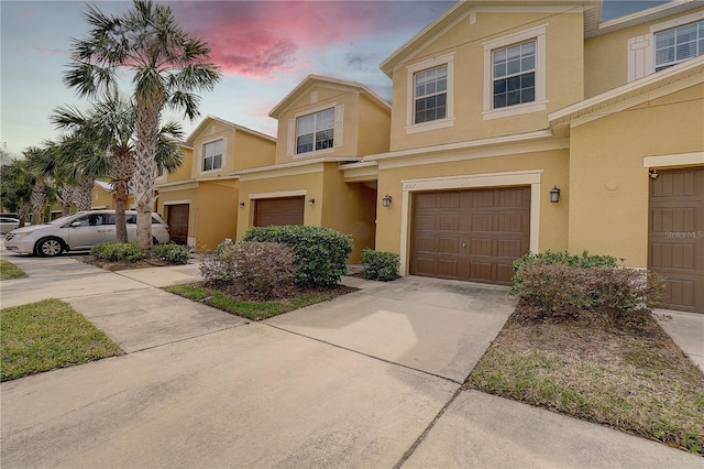 townhome / multi-family property featuring driveway, an attached garage, and stucco siding