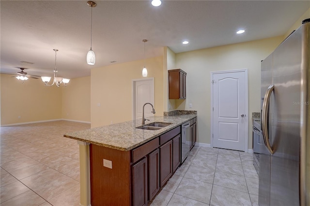 kitchen with stainless steel appliances, a peninsula, a sink, hanging light fixtures, and light stone countertops