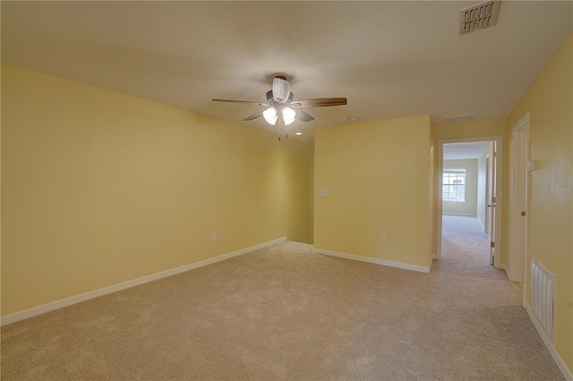 spare room with baseboards, a ceiling fan, visible vents, and light colored carpet