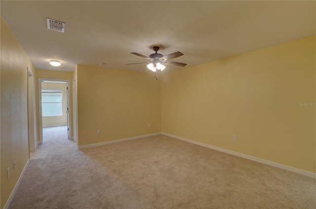 spare room featuring baseboards, visible vents, ceiling fan, and light colored carpet