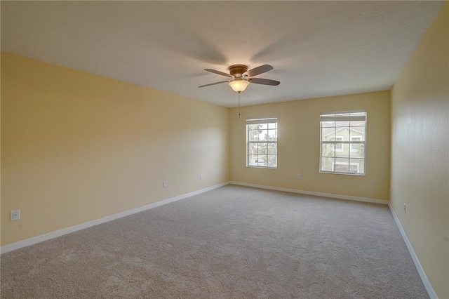 spare room with baseboards, ceiling fan, and light colored carpet