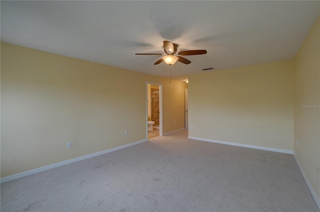 spare room with baseboards, visible vents, a ceiling fan, and light colored carpet