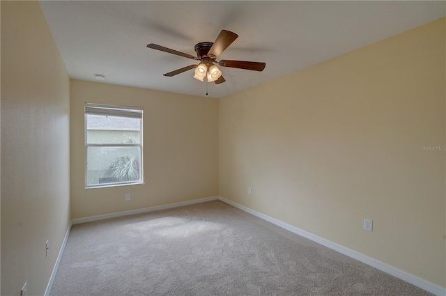 carpeted spare room with a ceiling fan and baseboards