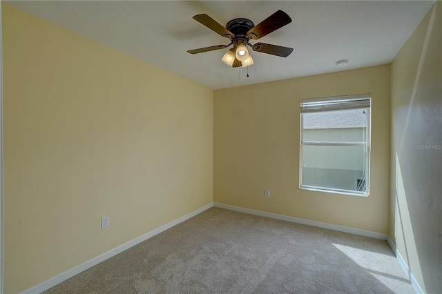 carpeted spare room featuring ceiling fan and baseboards