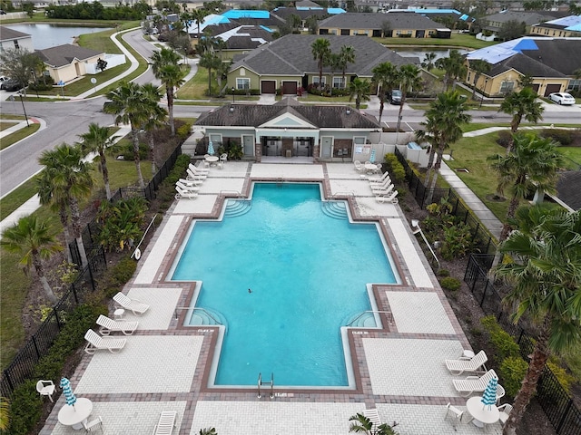 view of pool featuring a water view, a residential view, fence, and a patio