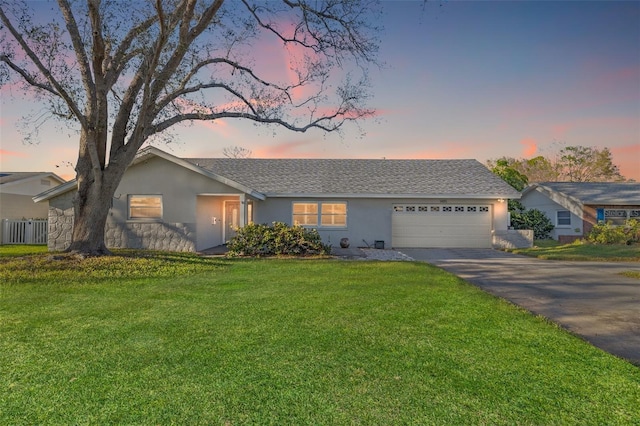 single story home featuring driveway, a garage, a lawn, and stucco siding