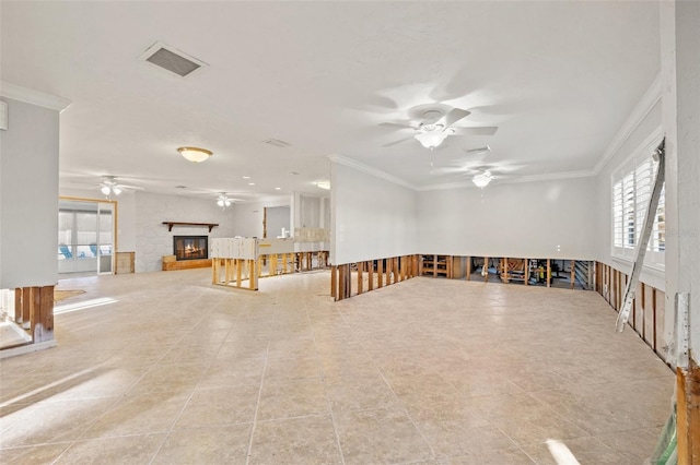 empty room with ceiling fan, a glass covered fireplace, visible vents, and crown molding