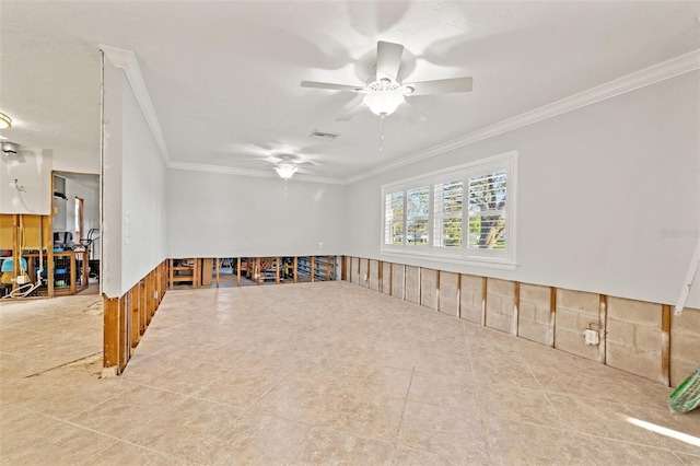 tiled spare room with a ceiling fan, wainscoting, visible vents, and crown molding