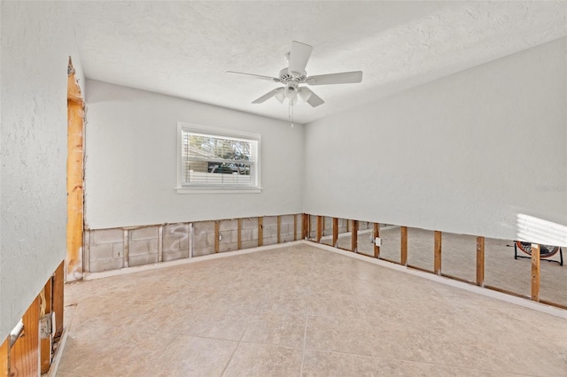 unfurnished room featuring ceiling fan, a textured ceiling, and a textured wall