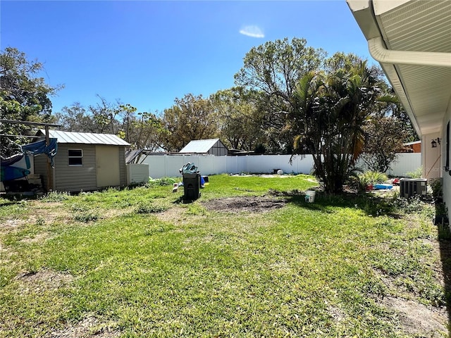 view of yard featuring a shed, an outdoor structure, a fenced backyard, and cooling unit