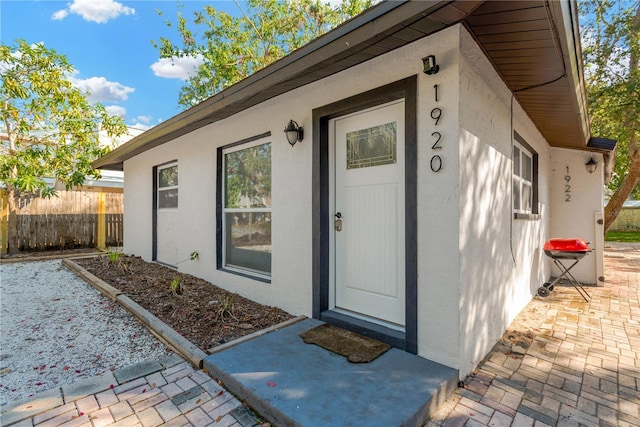 property entrance featuring fence and stucco siding