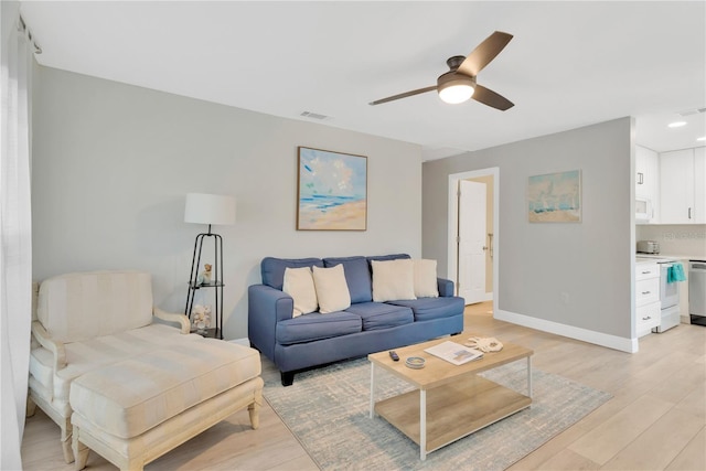 living area with baseboards, ceiling fan, visible vents, and light wood-style floors