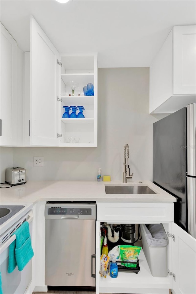 kitchen with a sink, white cabinets, light countertops, appliances with stainless steel finishes, and open shelves