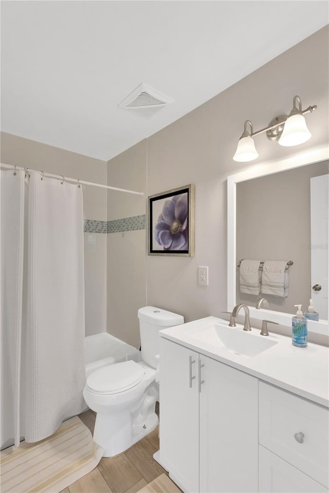 bathroom featuring visible vents, toilet, wood finished floors, shower / bath combination with curtain, and vanity