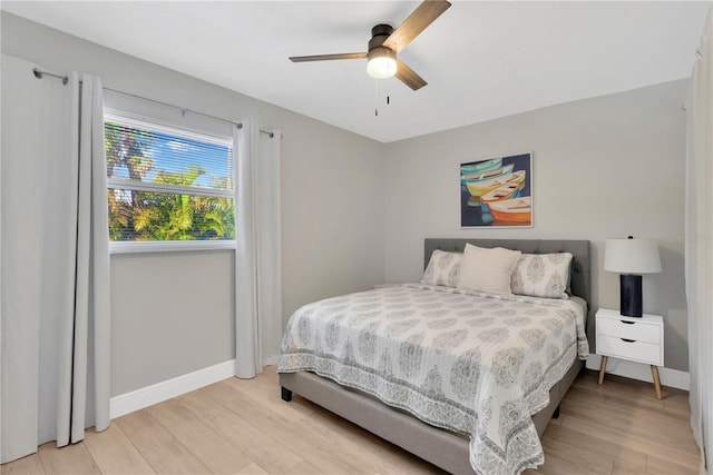 bedroom with light wood finished floors, ceiling fan, and baseboards