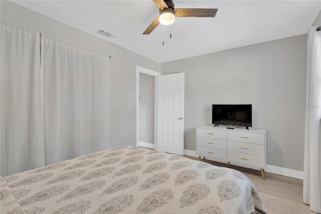 bedroom featuring light wood-style floors, visible vents, baseboards, and a ceiling fan