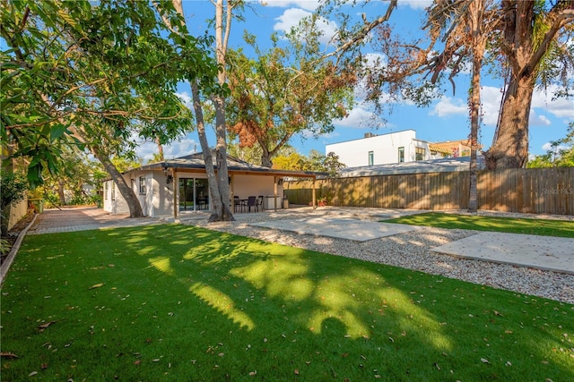 back of house featuring stucco siding, a fenced backyard, a lawn, and a patio