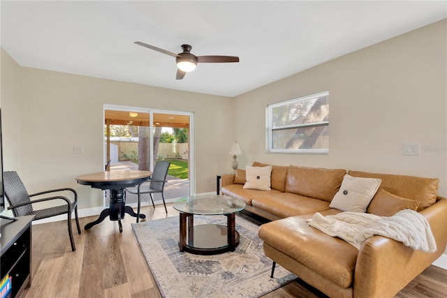 living room featuring a ceiling fan, baseboards, and wood finished floors