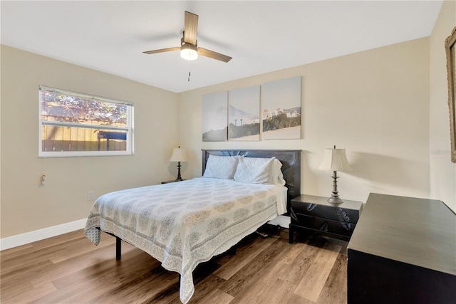 bedroom with ceiling fan, wood finished floors, and baseboards