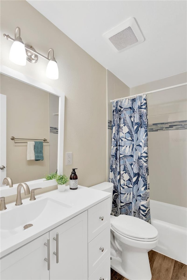 full bath featuring visible vents, toilet, shower / bath combo with shower curtain, vanity, and wood finished floors