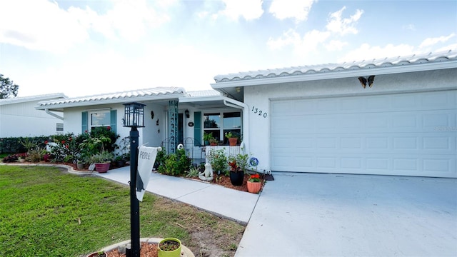 view of front of home featuring concrete driveway, a front lawn, a tiled roof, and stucco siding