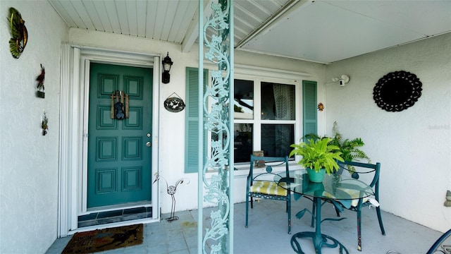 property entrance with covered porch and stucco siding