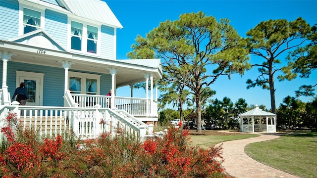 1320 Bottlebrush Dr, Bradenton, FL 34208 - view of side of home with a gazebo, covered porch, metal roof, a lawn, and stairs