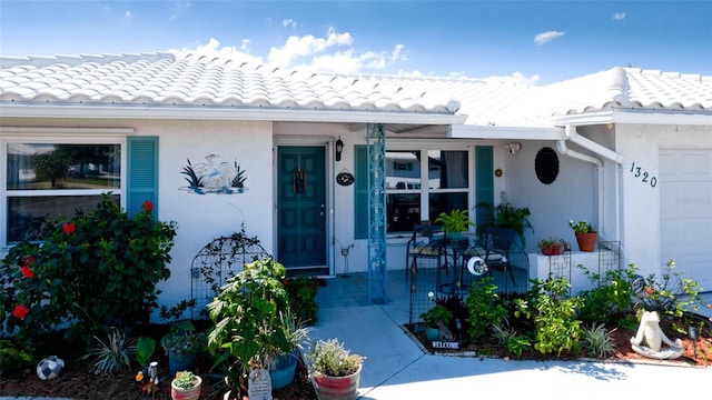 view of exterior entry with a tile roof and stucco siding