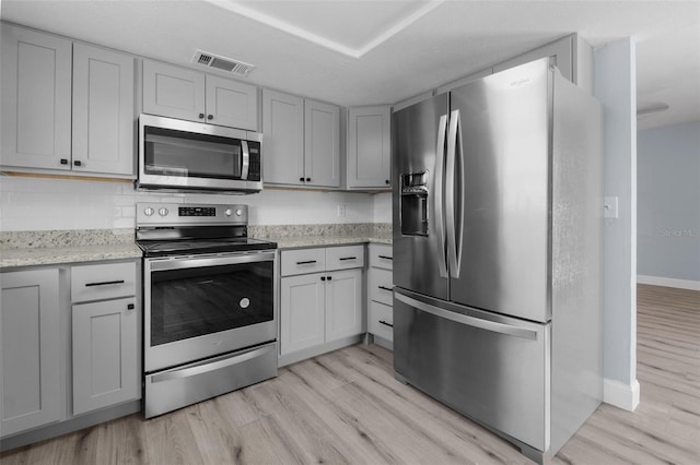 kitchen with appliances with stainless steel finishes, visible vents, light wood-style flooring, and gray cabinetry