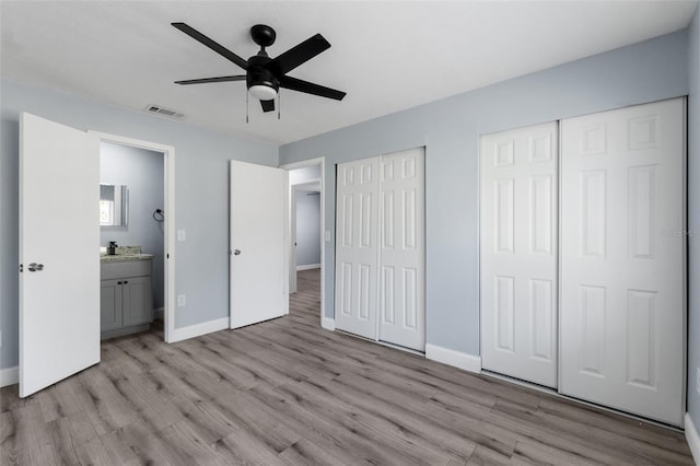 unfurnished bedroom with visible vents, baseboards, ceiling fan, light wood-style floors, and multiple closets