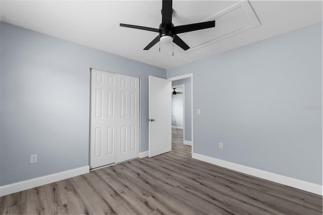 unfurnished bedroom with ceiling fan, a closet, wood finished floors, and baseboards