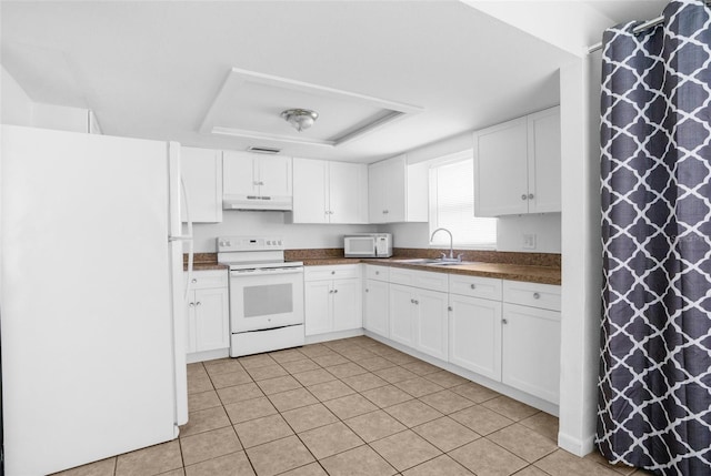 kitchen with under cabinet range hood, white appliances, a sink, white cabinets, and dark countertops