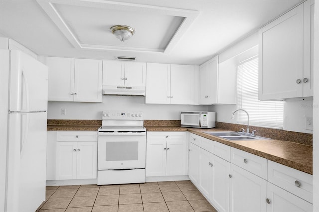 kitchen with a raised ceiling, white cabinets, a sink, white appliances, and under cabinet range hood