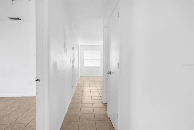 hall featuring visible vents, baseboards, and light tile patterned floors