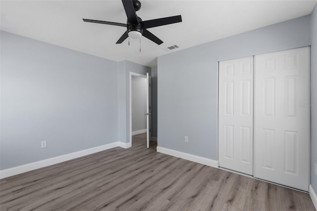 unfurnished bedroom featuring wood finished floors, a ceiling fan, visible vents, baseboards, and a closet