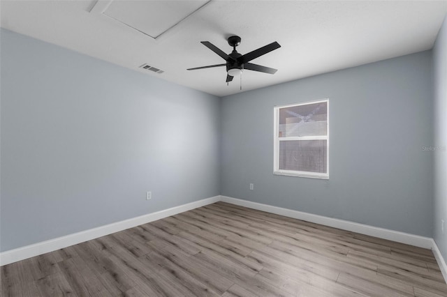 spare room featuring attic access, visible vents, baseboards, a ceiling fan, and wood finished floors