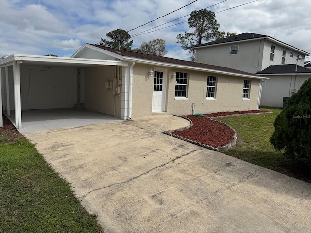 back of house featuring a carport, concrete driveway, a yard, and stucco siding