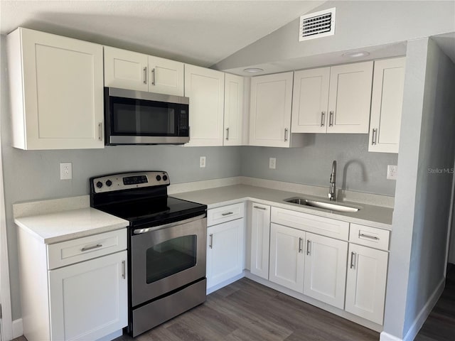 kitchen featuring visible vents, white cabinets, vaulted ceiling, stainless steel appliances, and a sink