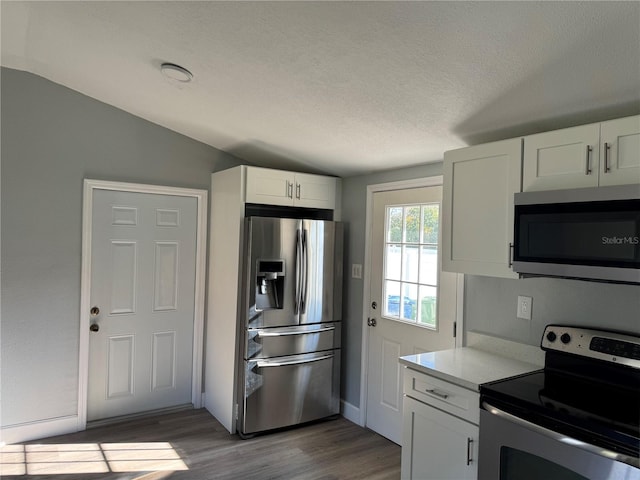 kitchen featuring dark wood-style floors, stainless steel appliances, light countertops, white cabinets, and a textured ceiling