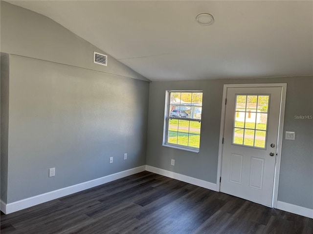 interior space with dark wood-type flooring, visible vents, vaulted ceiling, and baseboards