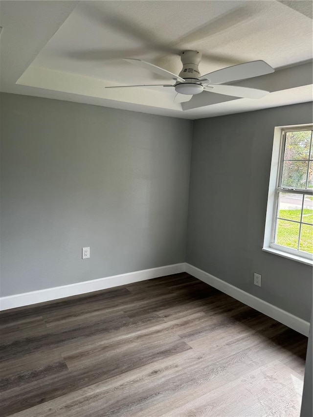 empty room featuring dark wood-type flooring, ceiling fan, and baseboards