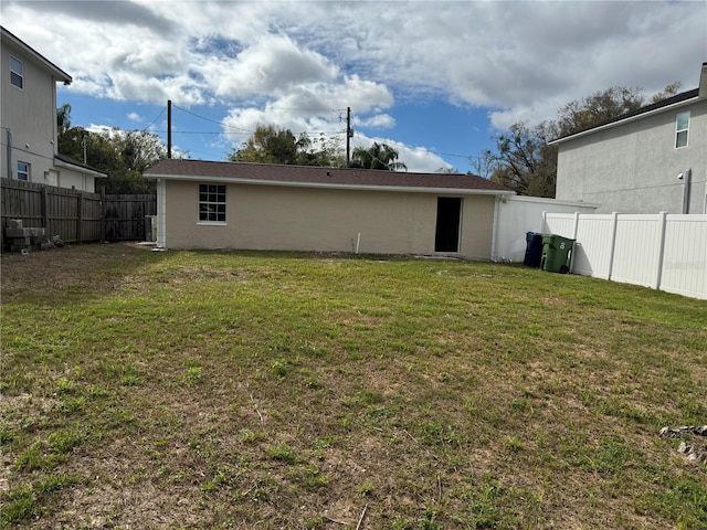 back of house featuring a fenced backyard, a yard, and stucco siding