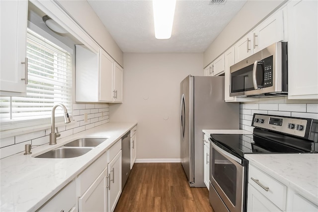 kitchen with a sink, decorative backsplash, dark wood-type flooring, white cabinets, and appliances with stainless steel finishes