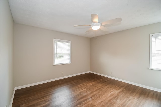 spare room with wood finished floors, a healthy amount of sunlight, and baseboards